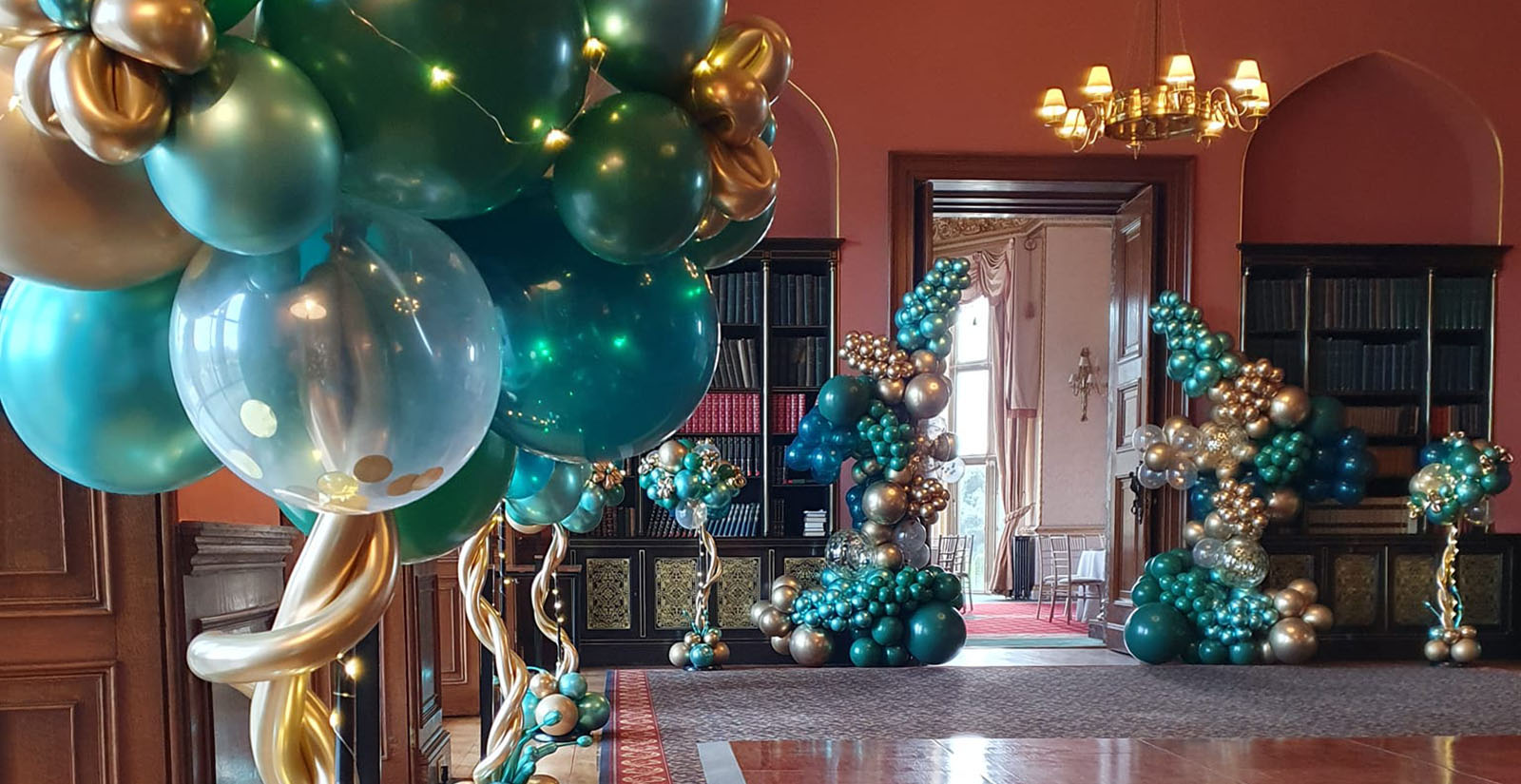 Green and gold organic balloon garlands and topiary trees